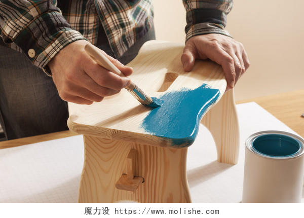 工匠在给木质的凳子上蓝色的油漆